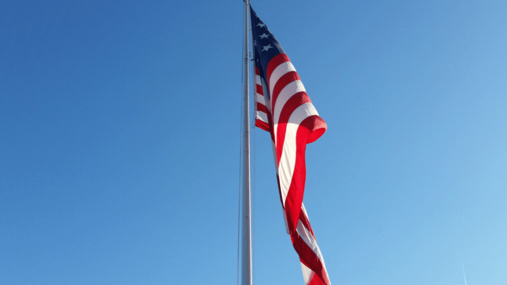 an american flag blowing in the wind against a blue sky