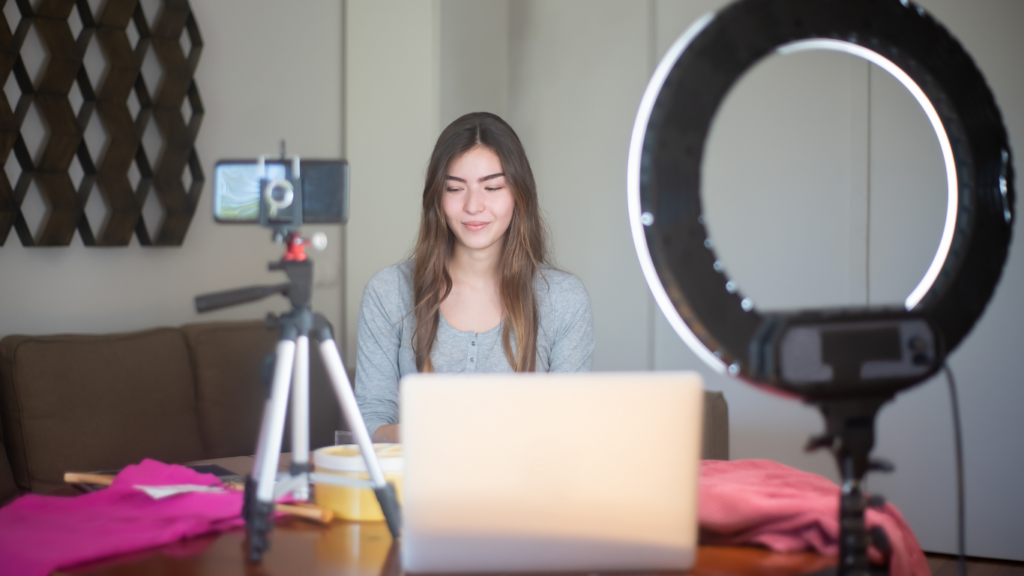 A person sitting in front of a laptop with a ring light