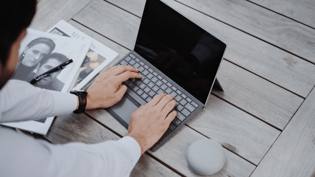 a person typing on a laptop on a wooden table