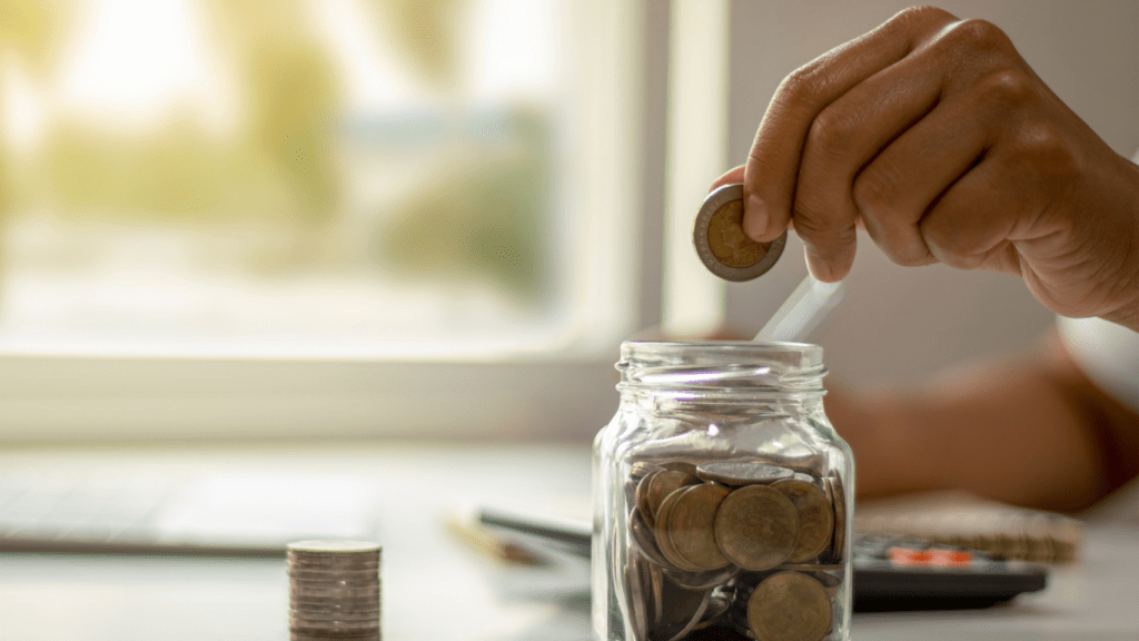 Putting coins in a jar on a table