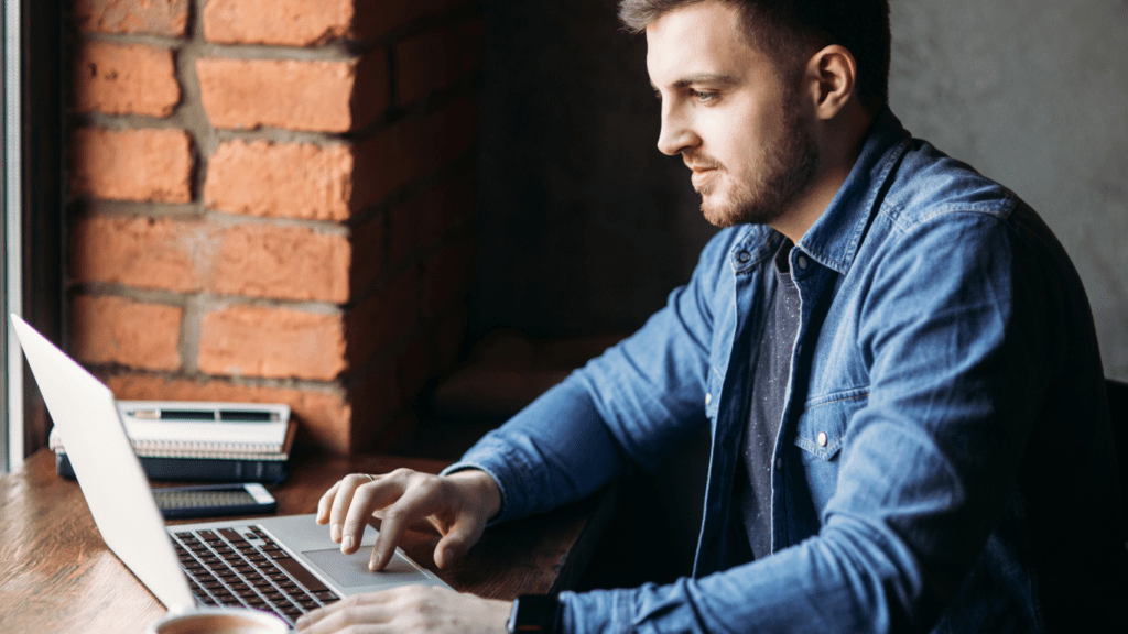 a person sitting at a table in front of a laptop