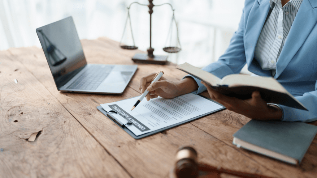 a person in a suit sitting at a desk with a scale of justice