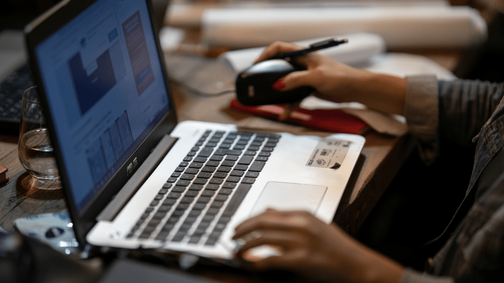 a person typing on a laptop on a wooden table