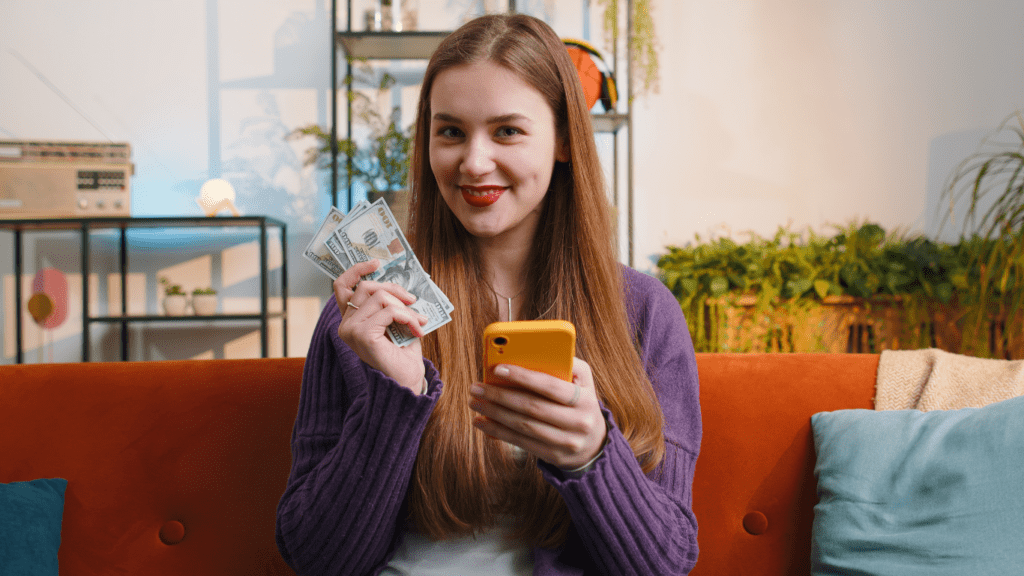 a smiling person holding money in their hand