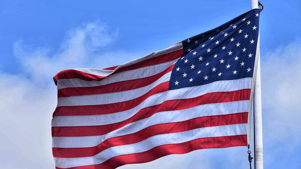 an american flag blowing in the wind against a blue sky