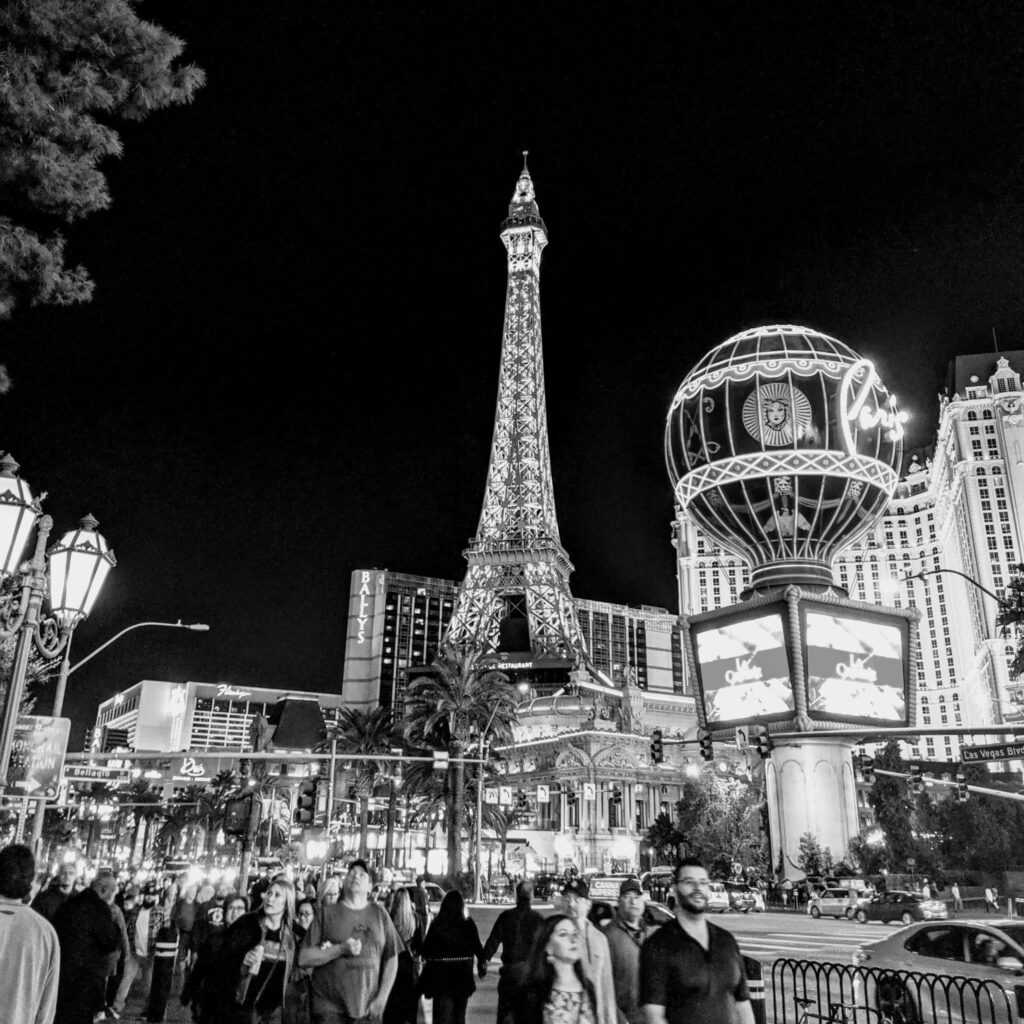 Monochrome view of Paris Las Vegas Hotel and Casino with vibrant evening crowd.